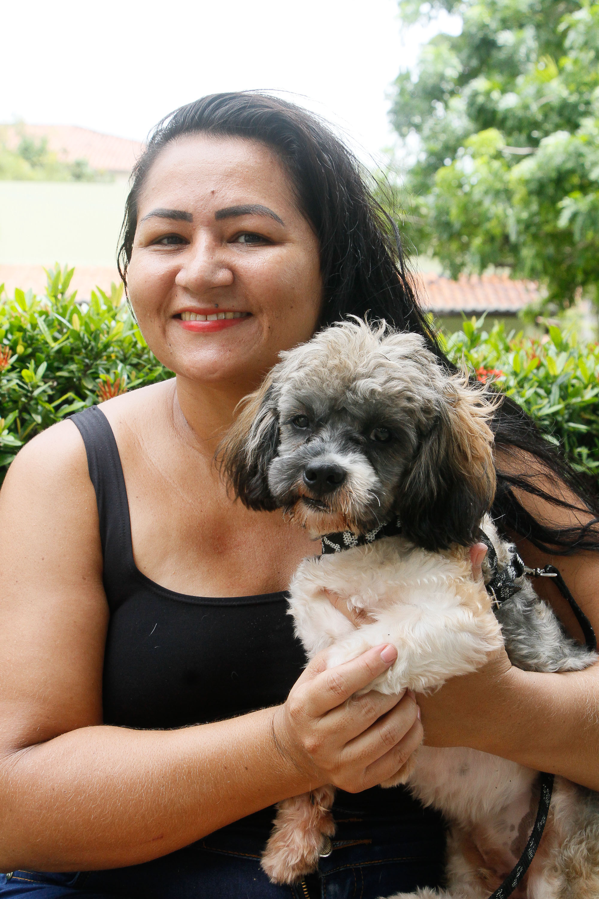 mulher segurando cachorro e sorrindo para a foto